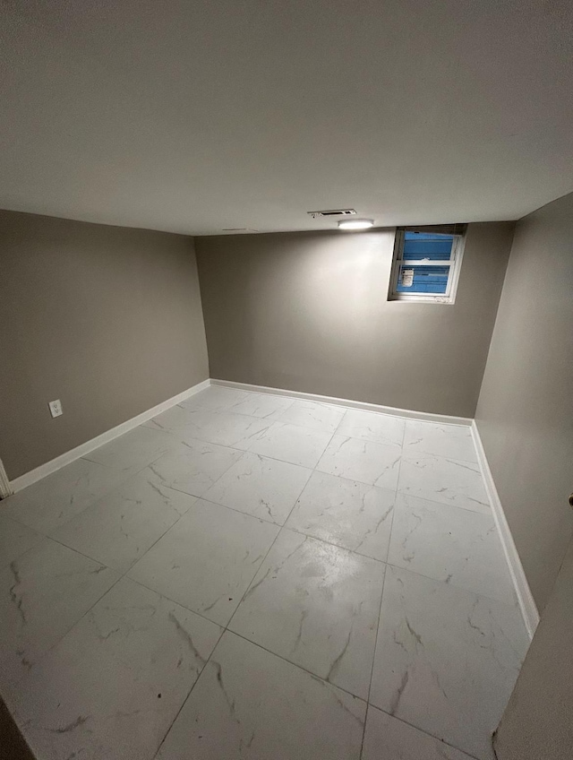 finished basement featuring marble finish floor, visible vents, and baseboards