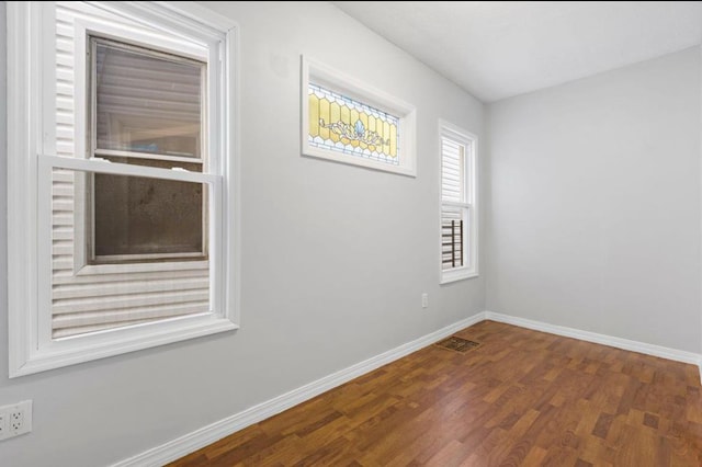 unfurnished room with visible vents, baseboards, and wood finished floors