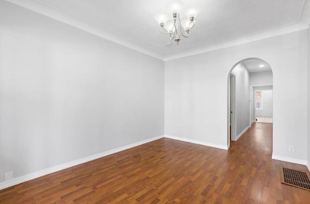 unfurnished room with arched walkways, crown molding, visible vents, wood finished floors, and baseboards