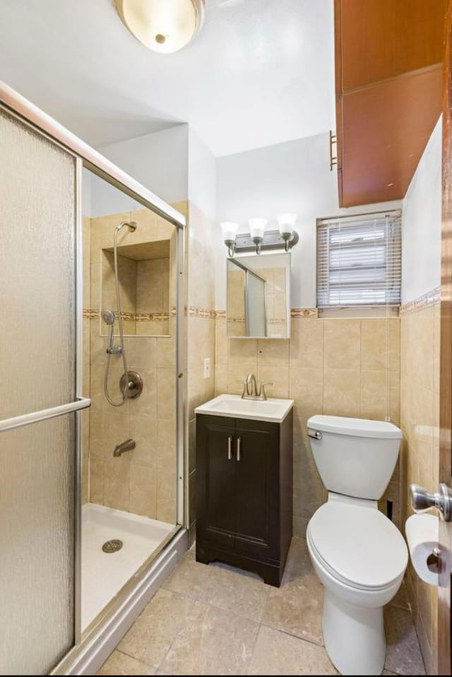 full bathroom with toilet, a shower stall, tile walls, and vanity