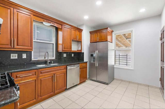 kitchen with light tile patterned flooring, stainless steel appliances, a sink, tasteful backsplash, and brown cabinetry