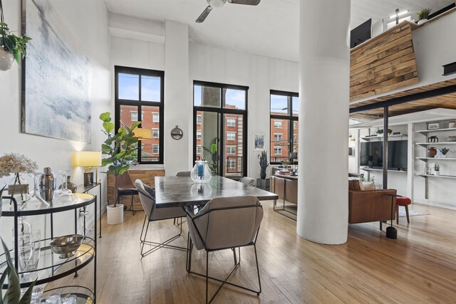 205 10th St Unit 3G, Jersey City, NJ 07302 - dining room featuring wood finished floors, plenty of natural light, a ceiling fan, a towering ceiling, and decorative columns