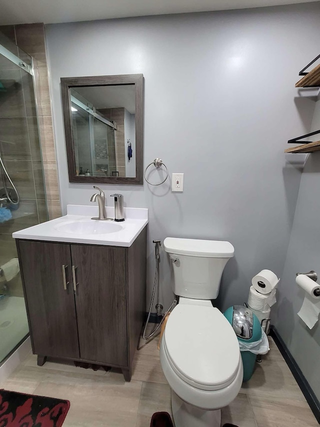 bathroom featuring a shower with door, vanity, and toilet