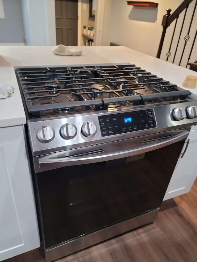 interior details with dark hardwood / wood-style flooring, white cabinets, and stainless steel gas range