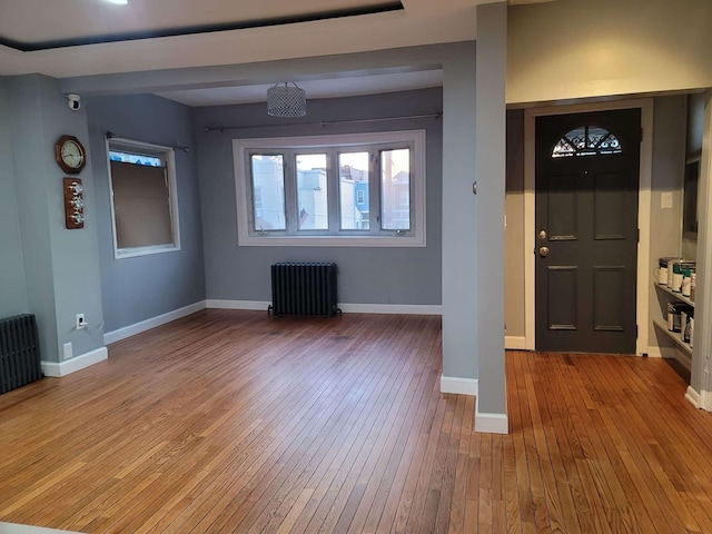 unfurnished living room featuring hardwood / wood-style floors and radiator heating unit