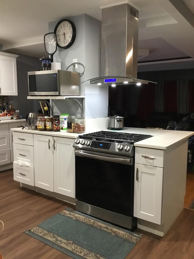 kitchen with island exhaust hood, appliances with stainless steel finishes, dark hardwood / wood-style flooring, and white cabinets