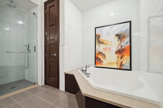 bathroom featuring plus walk in shower, tile patterned flooring, and tile walls