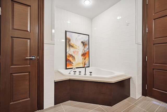 bathroom with tile walls, a washtub, and tile patterned floors