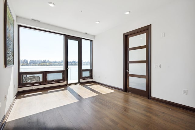 unfurnished room with wood-type flooring and a water view