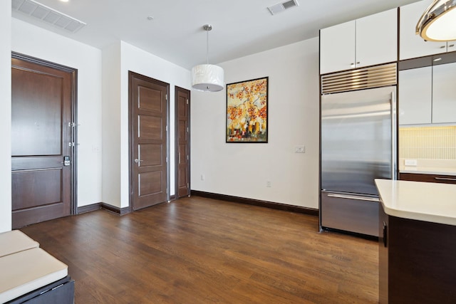 kitchen with white cabinetry, stainless steel built in fridge, dark wood-type flooring, and decorative light fixtures