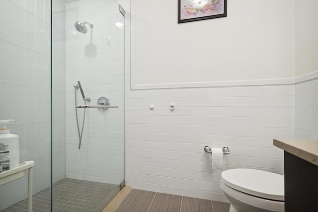 bathroom featuring tiled shower, vanity, toilet, and tile walls
