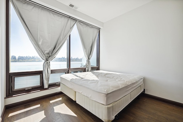 bedroom featuring a water view and dark hardwood / wood-style flooring