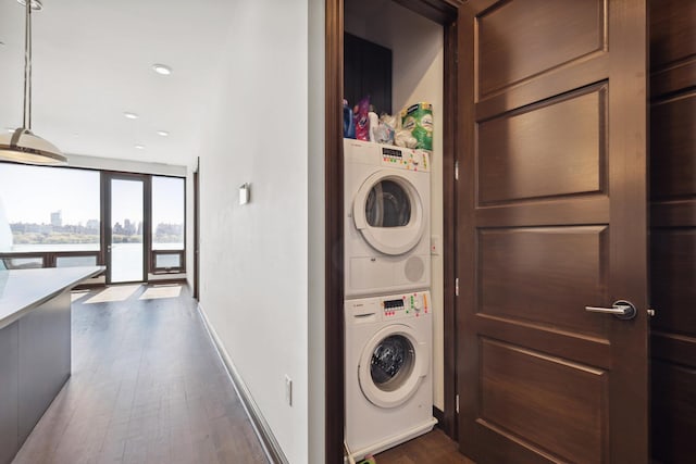laundry room with stacked washer / dryer and dark wood-type flooring