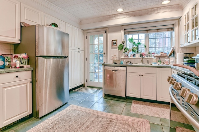 kitchen featuring tasteful backsplash, white cabinets, and appliances with stainless steel finishes