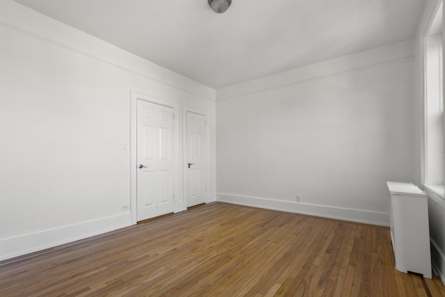 spare room with hardwood / wood-style floors and baseboards