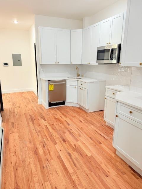 530 45th St, Union City, NJ 07087 - kitchen with appliances with stainless steel finishes, light wood-style flooring, light countertops, electric panel, and white cabinetry