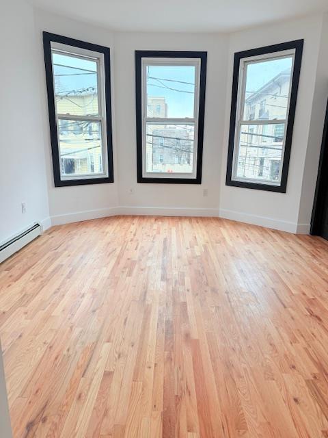 530 45th St, Union City, NJ 07087 - unfurnished room featuring light wood-style flooring, healthy amount of natural light, and a baseboard radiator