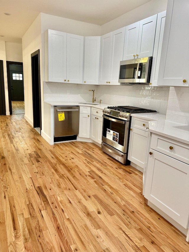 530 45th St, Union City, NJ 07087 - kitchen with appliances with stainless steel finishes, light countertops, light wood-type flooring, tasteful backsplash, and white cabinets