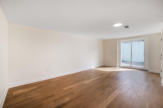 spare room with baseboards, visible vents, and wood finished floors