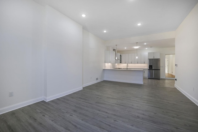 unfurnished living room with recessed lighting, a sink, dark wood finished floors, and baseboards