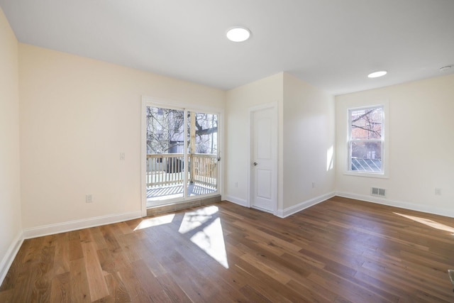 spare room featuring visible vents, baseboards, and wood finished floors