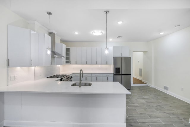 kitchen with visible vents, wall chimney exhaust hood, appliances with stainless steel finishes, light countertops, and a sink