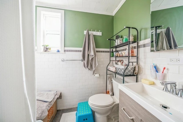 bathroom with toilet, tile patterned flooring, tile walls, ornamental molding, and vanity