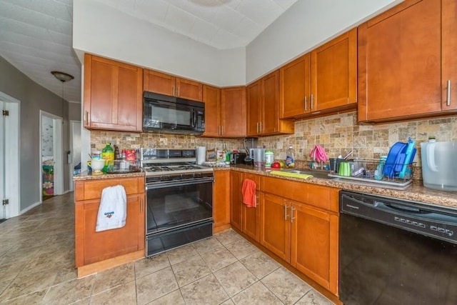 kitchen with light stone counters, black appliances, and tasteful backsplash