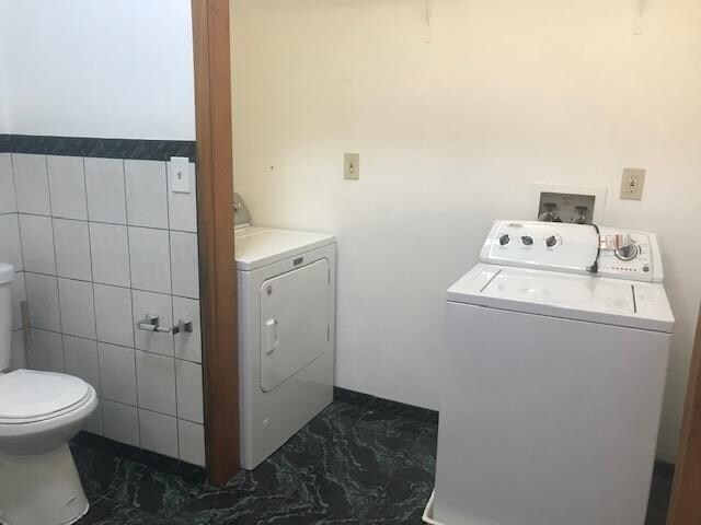 washroom with washer and dryer and tile walls