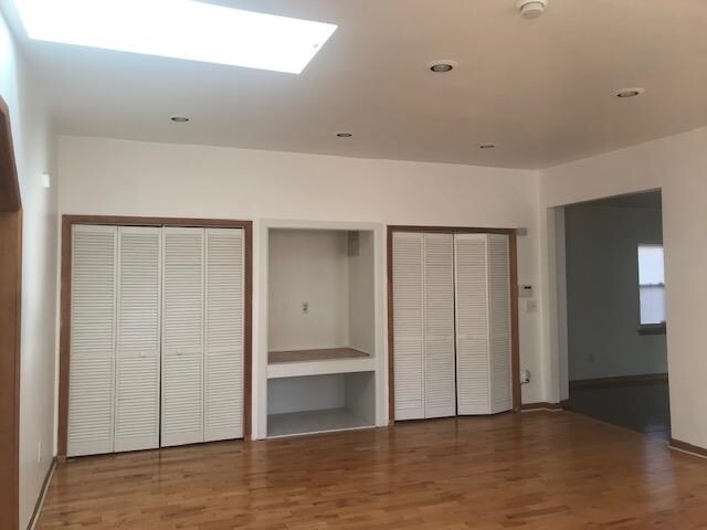 unfurnished bedroom featuring multiple closets and hardwood / wood-style flooring