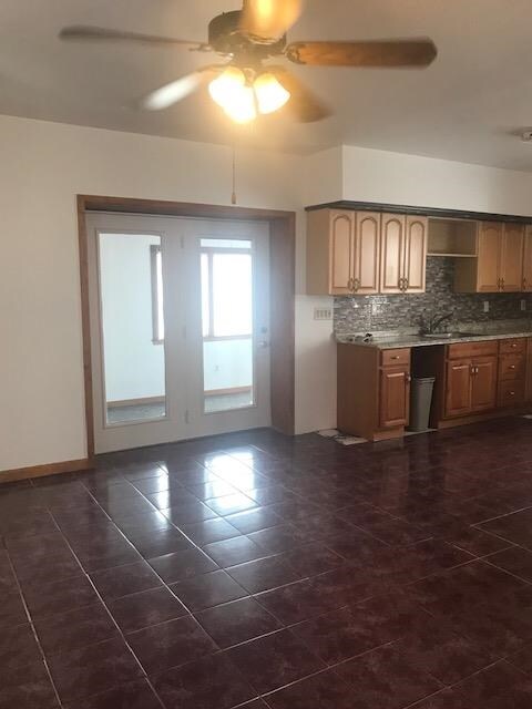 kitchen with dark tile patterned floors, backsplash, sink, and ceiling fan