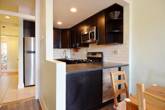 kitchen with backsplash, dark brown cabinetry, stainless steel appliances, sink, and light hardwood / wood-style flooring