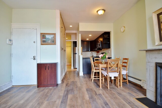 dining room with light hardwood / wood-style floors and a baseboard heating unit