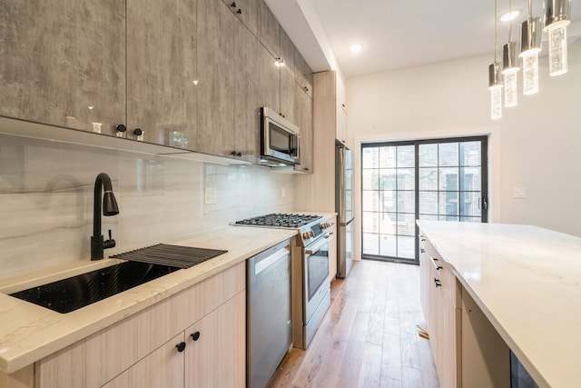 kitchen featuring light hardwood / wood-style floors, sink, appliances with stainless steel finishes, light brown cabinetry, and decorative light fixtures