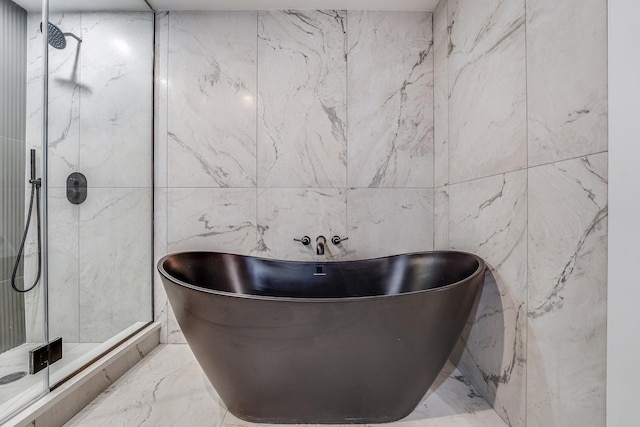 bathroom featuring tile walls, a soaking tub, a shower stall, and marble finish floor