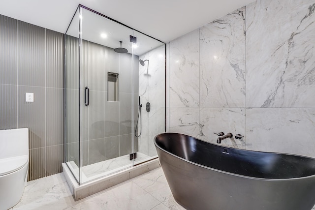 bathroom featuring a freestanding bath, marble finish floor, a shower stall, and tile walls