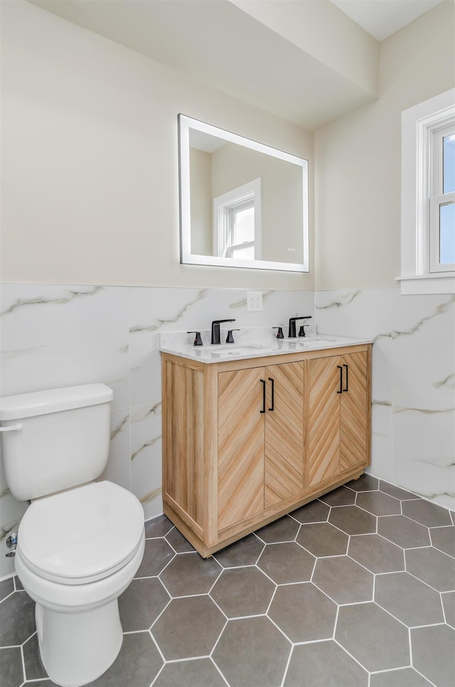 275 Pearsall Ave Unit 2, Jersey City, NJ 07305 - bathroom featuring tile walls, toilet, a wainscoted wall, a sink, and double vanity