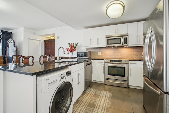 88 Morgan St Unit 2206, Jersey City, NJ 07302 - kitchen with appliances with stainless steel finishes, washer / dryer, a peninsula, backsplash, and dark tile patterned floors