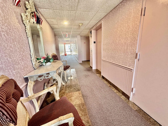 hallway featuring wallpapered walls, a paneled ceiling, and a wainscoted wall