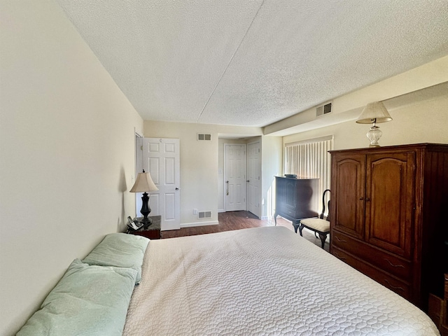 bedroom featuring dark wood-style floors, visible vents, and a textured ceiling