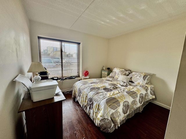 bedroom featuring baseboards, a textured ceiling, and wood finished floors