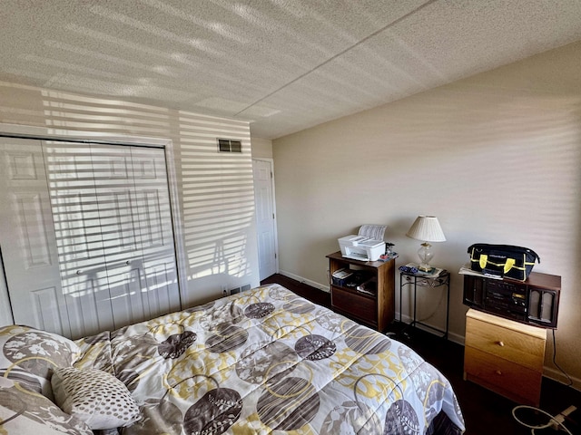 bedroom with visible vents, a textured ceiling, and baseboards