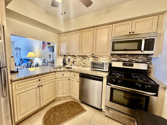 kitchen featuring light stone countertops, tasteful backsplash, appliances with stainless steel finishes, and cream cabinets