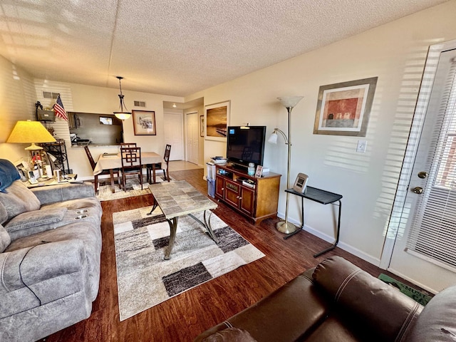 living area with dark wood-style floors, visible vents, a textured ceiling, and baseboards