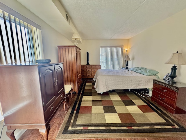 bedroom featuring dark wood finished floors, visible vents, and a textured ceiling