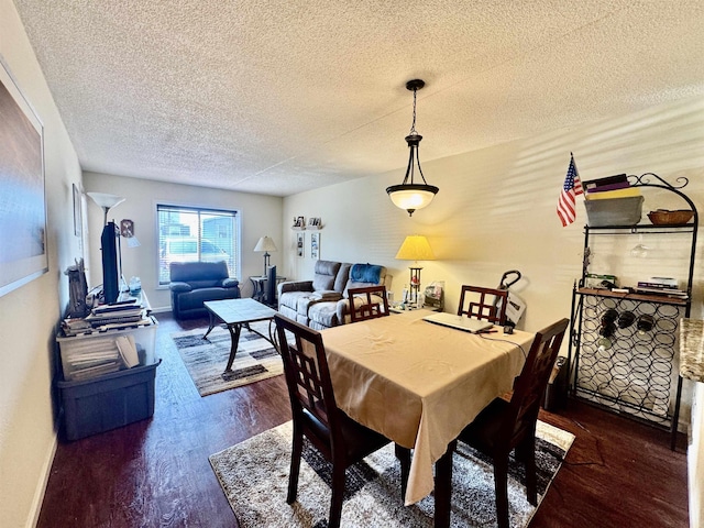 dining space with a textured ceiling, baseboards, and wood finished floors