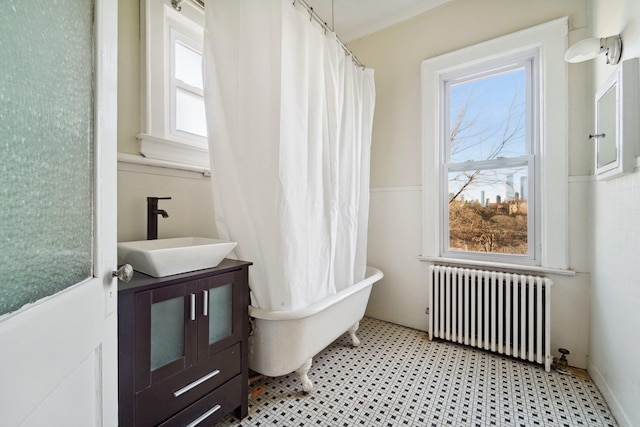 bathroom with a bath, radiator, and vanity