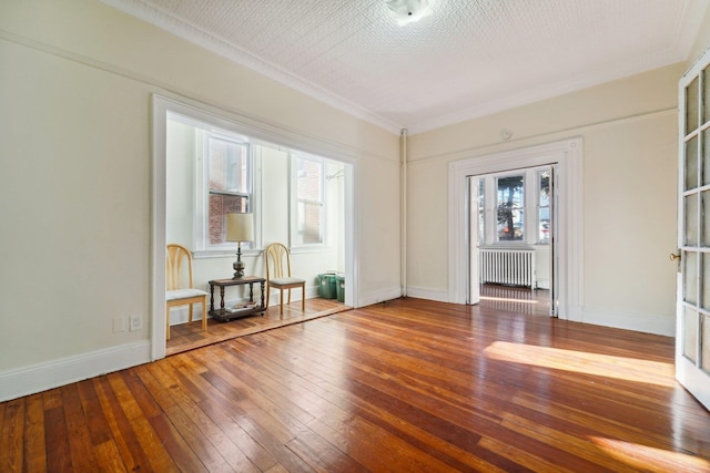 unfurnished room with radiator heating unit, hardwood / wood-style flooring, a wealth of natural light, and ornamental molding