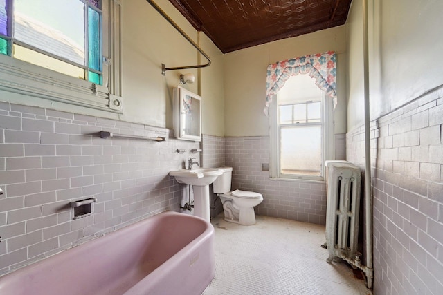 bathroom with toilet, radiator heating unit, wood ceiling, tile walls, and a bathing tub