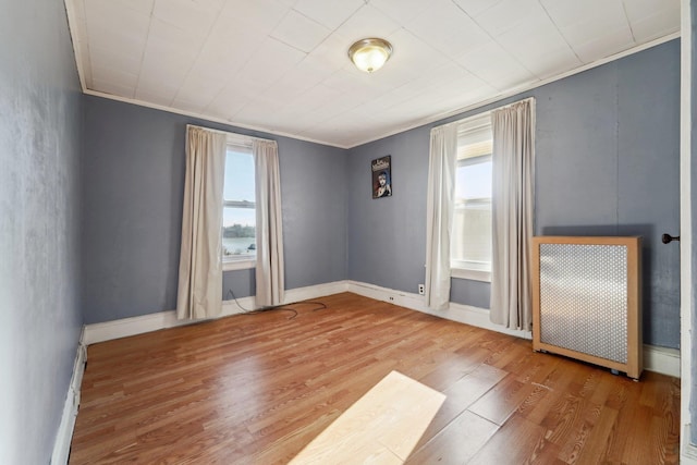 empty room with hardwood / wood-style flooring, radiator heating unit, and ornamental molding